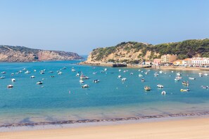 A coastal scene with numerous boats anchored in clear blue waters, a sandy beach, and buildings on a hillside. - Apartment with Stunning Beach View, Very Cozy and Comfortable (SÃO MARTINHO DO PORTO)