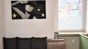 A modern living room with a sectional sofa, a glass coffee table, and a large window offering a view of the cityscape. - Great price in the old town and center, nice view, central, cozy with heart (Heidelberg)