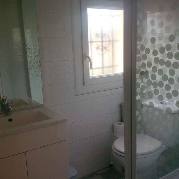 Un bagno con un lavandino bianco, un water e una finestra che si affaccia su degli alberi.