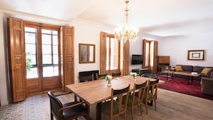 A spacious living area with a wooden dining table, chairs, a chandelier, a sofa, and a television. - DIWAN Suite apart. 4BDR / 5BTH - Atocha / City Center (Madrid)