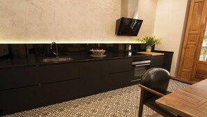 A modern kitchen with a black countertop, a built-in oven, and a black wall-mounted TV. - DIWAN Suite apart. 4BDR / 5BTH - Atocha / City Center (Madrid)