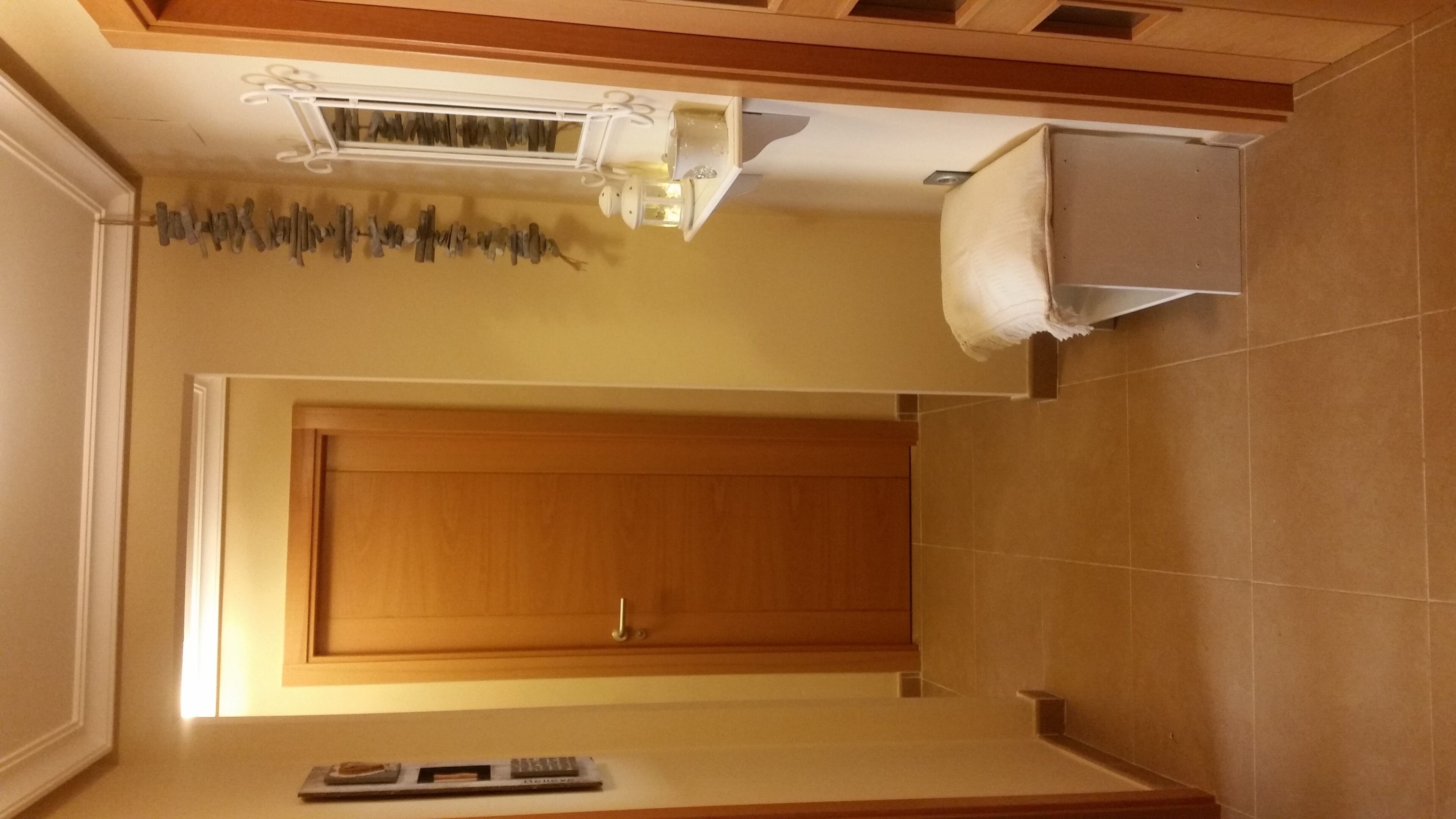 Et køkken med en trædør, en hvid bordplade og en ventilation i loftet.