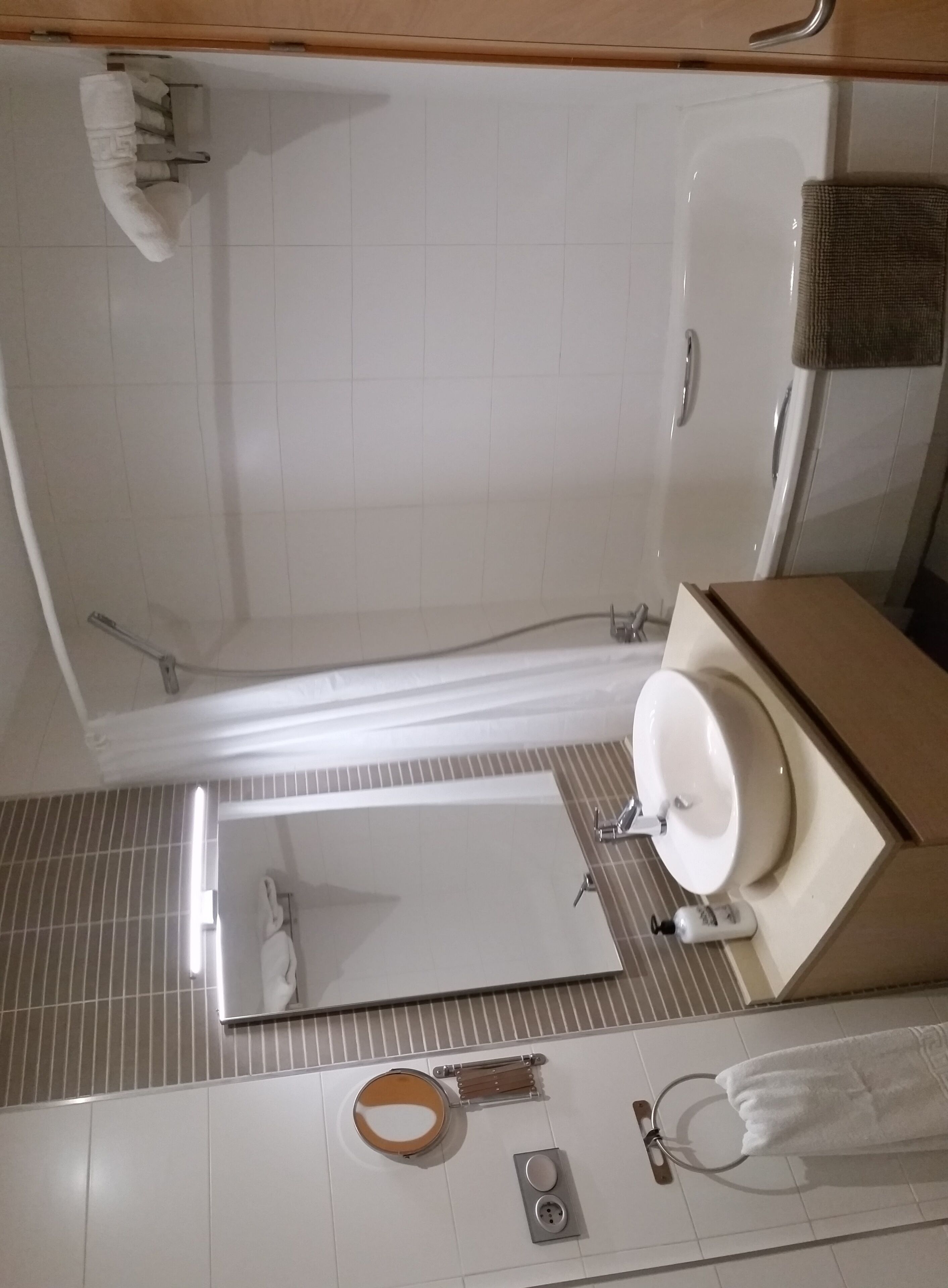 Un baño con bañera, lavabo, espejo, toallero y retrete.