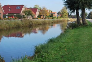 A calm river with houses on one side and a grassy bank on the other.