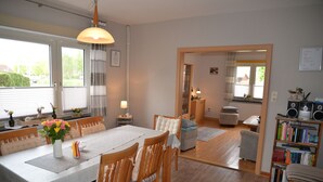 A dining area with a table set for four, wooden chairs, a vase of flowers, and a bookshelf with books. - Vacation home Lilli 35610 - Holiday home Lilli (Uplengen)