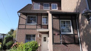 A two-story brick house with a tiled roof, multiple windows, and a front door.