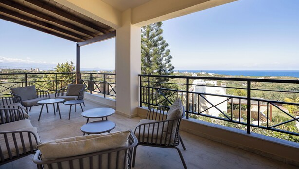 Un balcon avec des meubles d’extérieur, une vue sur la mer et un pin.