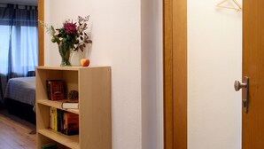 A hallway with a wooden bookshelf, a clock on the wall, and a door leading to another room. - 2-room apartment for 1 - 4 people (Bergisch Gladbach)