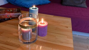 A room with a wooden table holding candles, a book, and a framed cityscape. - 2-room apartment for 1 - 4 people (Bergisch Gladbach)