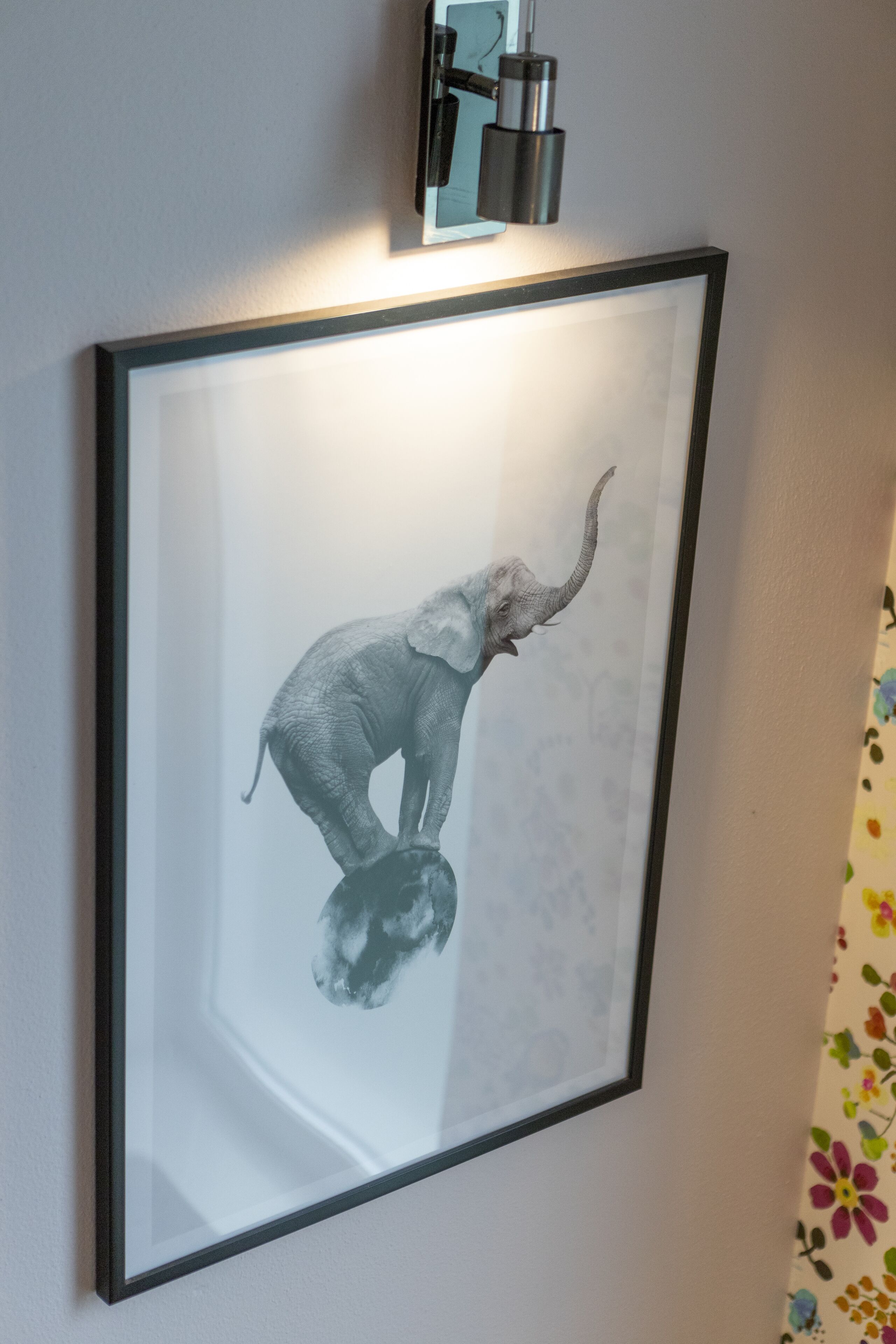 A framed artwork of an elephant on a wall.