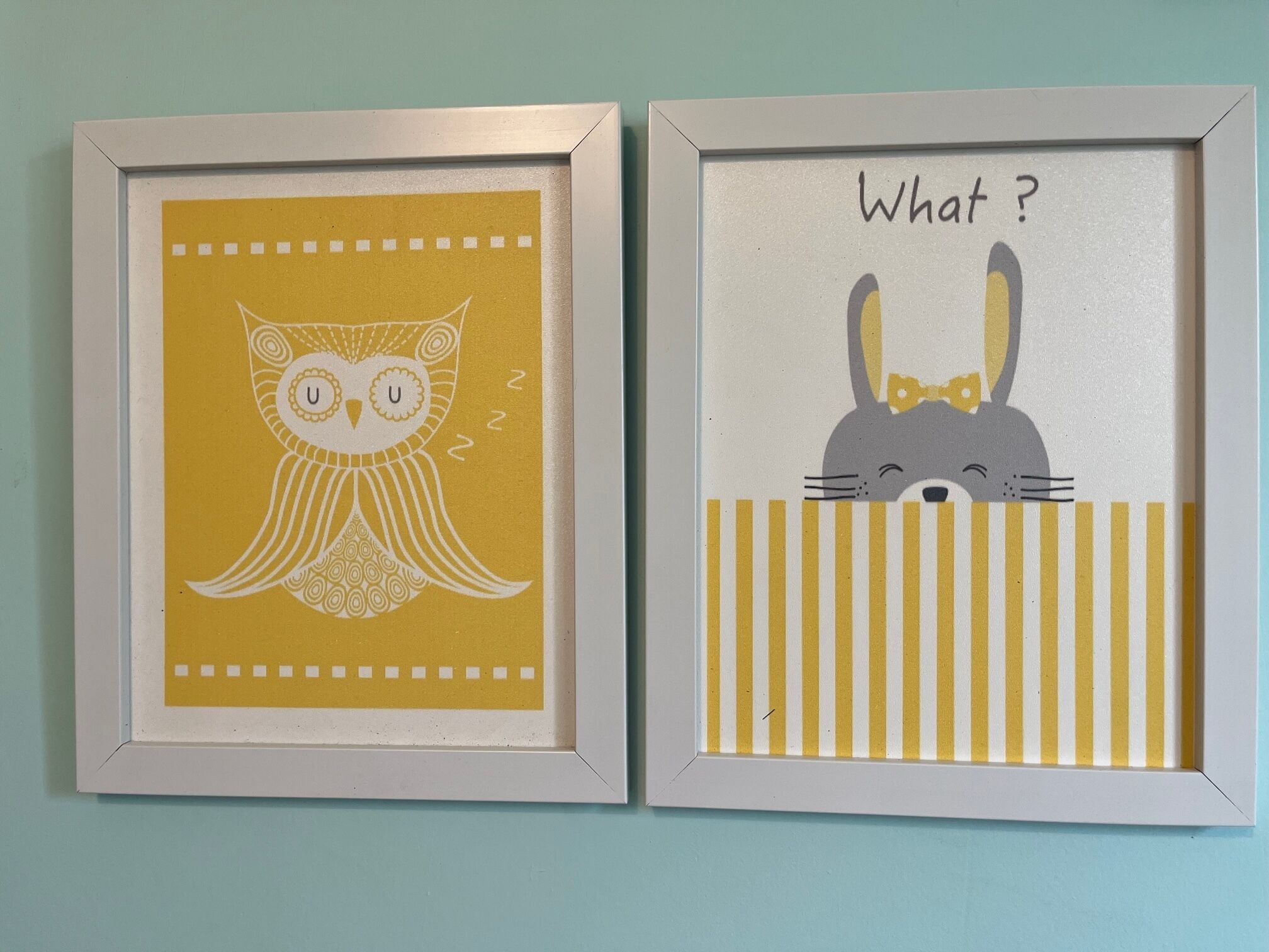 Dos obras de arte enmarcadas: una con un búho de ojos cerrados y la otra con un conejo asomándose sobre una valla con un bocadillo de diálogo que dice "¿Qué?".