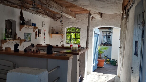 Een rustieke keuken met houten planken, een bargedeelte en uitzicht op de tuin door een raam.
