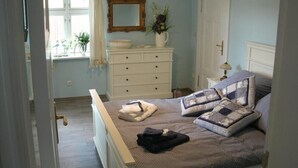 Een slaapkamer met een bed, een kaptafel en een raam met gordijnen.
