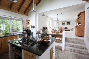 A spacious kitchen with a central island, wooden cabinets, and a view of the outdoors.