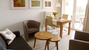 A modern living room with a sofa, two armchairs, a dining table with chairs, and artwork on the wall. - 2 room apartment 36 sqm for 2 guests Swimming pool and sauna approx. 8 minutes walk to the beach WLAN (Zinnowitz)