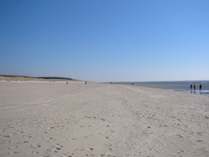 A wide sandy beach with footprints and a few people walking. - directly on the beach, balcony overlooking the sea, beach chair, close to the golf course (Wyk)