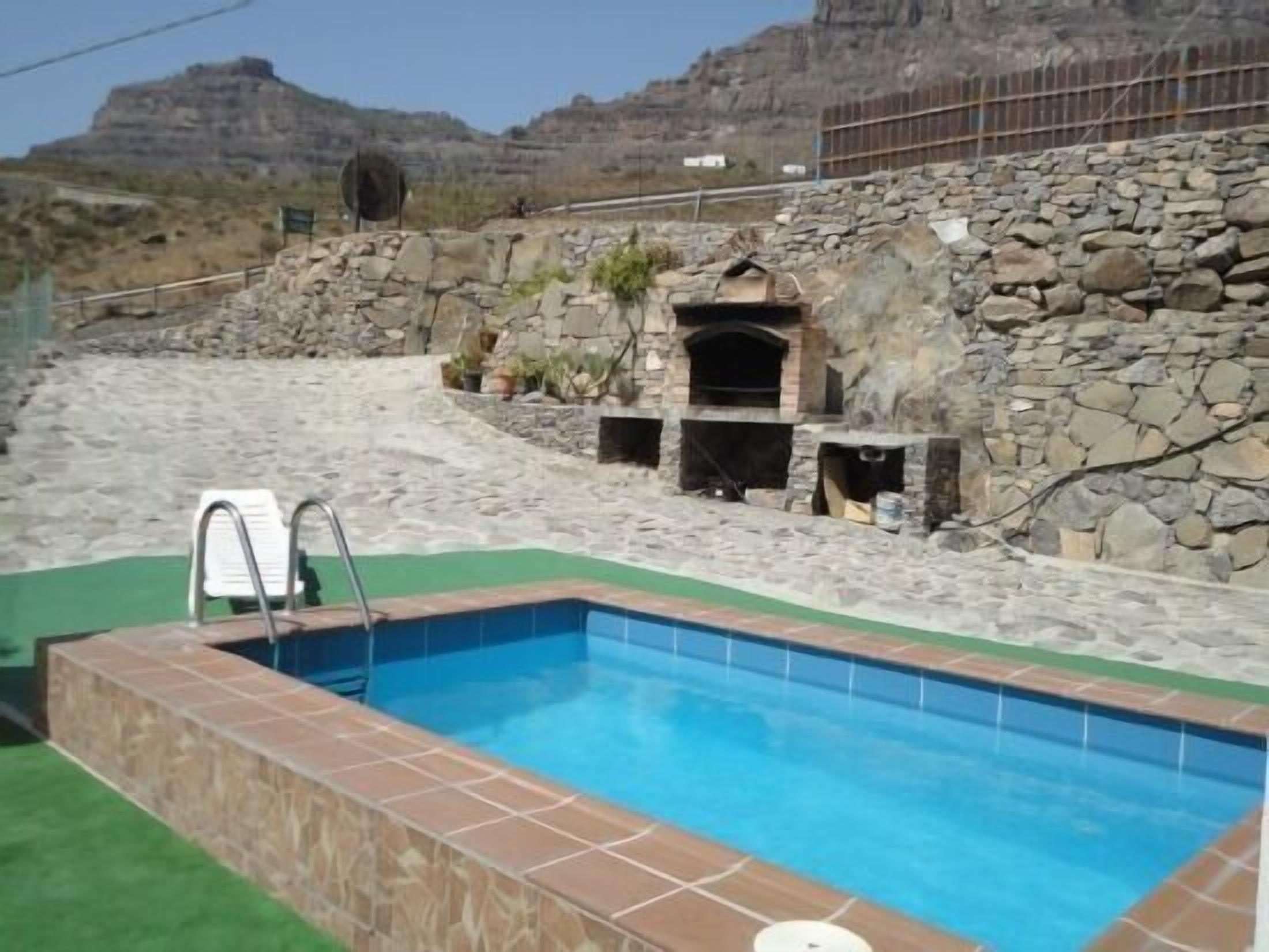 A swimming pool with stone walls and a stone fireplace.