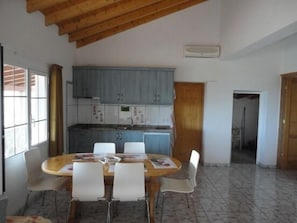 Enjoy meals together at the central dining table, surrounded by a well-equipped kitchen and comfortable living space.