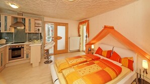 Quarto com cama grande, cozinha e banheiro.