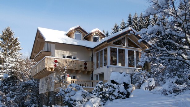 Um edifício grande, de vários andares, com telhado coberto de neve e varandas.