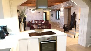 Eine moderne Küche mit einer zentralen Kochinsel, einem integrierten Backofen und einem Essbereich mit einem roten Sofa und einem Holztisch.