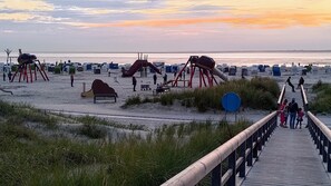 Une plage avec une promenade en bois menant à des chaises de plage et des parasols.