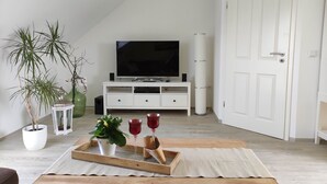 A modern living room with a white entertainment unit, a flat-screen TV, and a wooden coffee table with decorative items.
