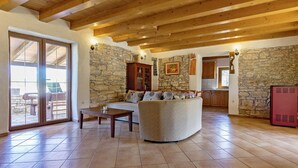 Ein geräumiger Wohnbereich mit Steinwand, Holzbalken an der Decke und einem großen Sofa.