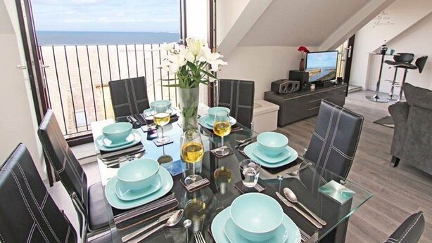 A dining area with a balcony view, a TV, and modern furniture.