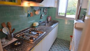 Una cocina con estufa a gas, un lavamanos y un ventanal.