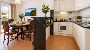 A modern kitchen with white cabinets, a black countertop, and a dining area with a table set for four. - 8 bedroom Villa Bella, Private Pool, Albufeira  Close to Strip & Old Town (Albufeira)