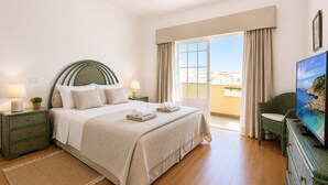A hotel room with a bed, a television, a balcony with curtains, and a view of the sea. - 8 bedroom Villa Bella, Private Pool, Albufeira  Close to Strip & Old Town (Albufeira)