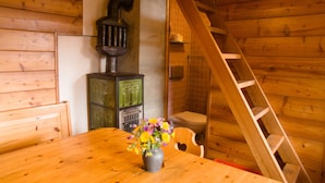 A wooden interior with a wooden table, a vase with flowers, a green cabinet, and a wooden ladder. - Magic chalet for 2 people (Villaz/la Sage - Evolène)