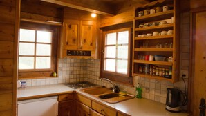A wooden cabin kitchen with a sink, stove, and shelves with kitchenware. - Magic chalet for 2 people (Villaz/la Sage - Evolène)
