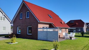 A two-story house with a red roof, a small attached garage, and a well-maintained lawn. - Vacation home at the Wangermeer, 3 bedrooms up to 8 pers. charging station / wallbox (Hohenkirchen)