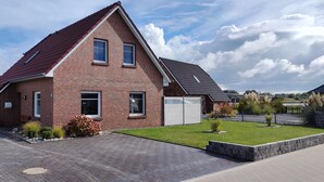 Een tweelaags bakstenen huis met een rood dak, een garage en een verzorgd gazon.