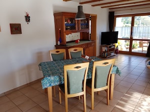 Enjoy meals in this dining area with a table for four, a cabinet, TV, and bookshelf.
