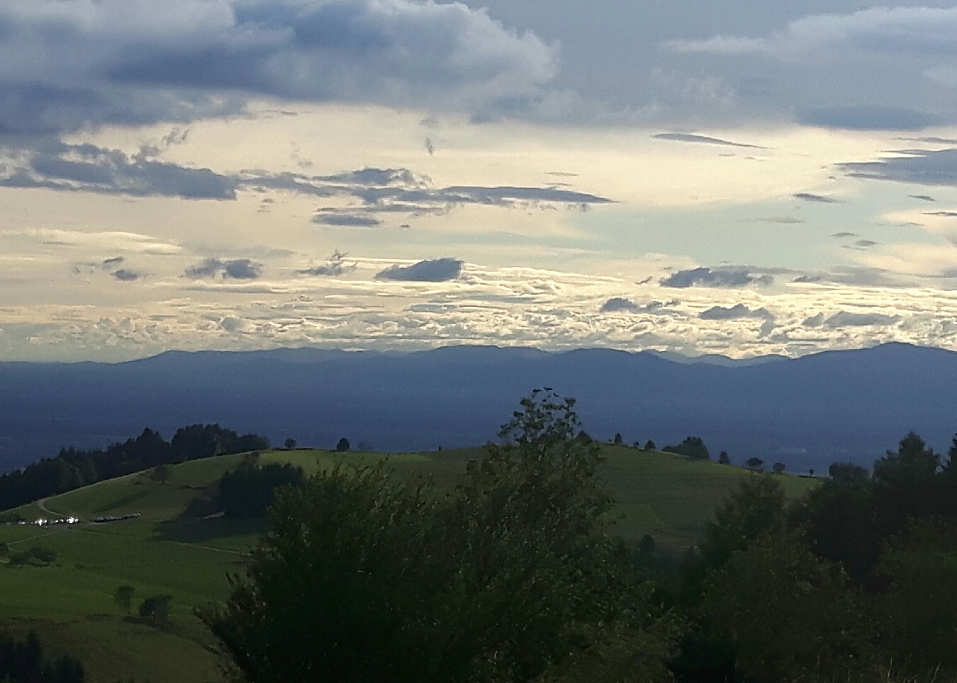 A panoramic view of a mountainous landscape with rolling hills and a cloudy sky.