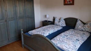 Ein Schlafzimmer mit einem hölzernen Bett, einem Nachttisch, einer Lampe und einem Kleiderschrank.