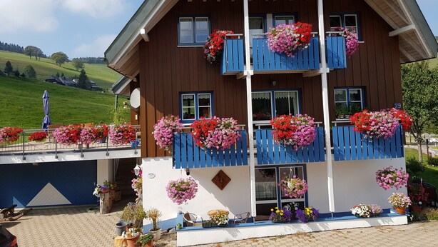 Ein zweistöckiges Holzhaus mit Balkonen, die mit Blumenkästen geschmückt sind.
