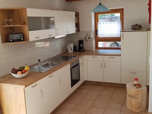 A kitchen with white cabinets, a wooden countertop, a sink, a coffee maker, and a bowl of fruit. - Modern and cosy holiday flat on the Freiburger mountain at Schauinsland (Oberried)