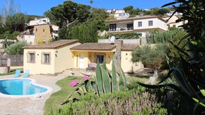A residential area with a swimming pool, a small building with a stone facade, and surrounding greenery. - Beautiful house surrounded by an idyllic garden with salt water pool. (Calonge)