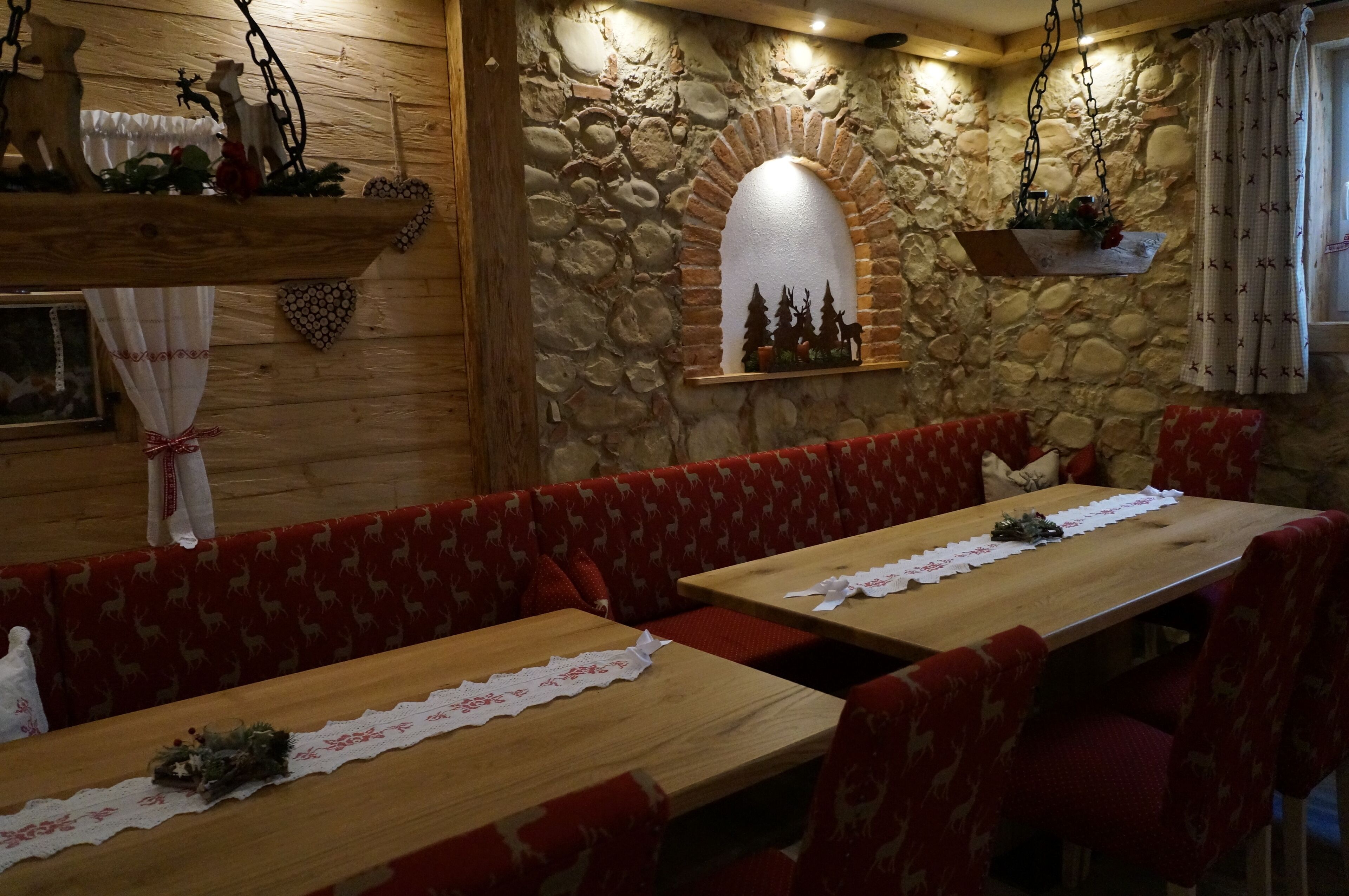 Un restaurant acollidor amb parets de pedra, seients de fusta i decoracions penjades.