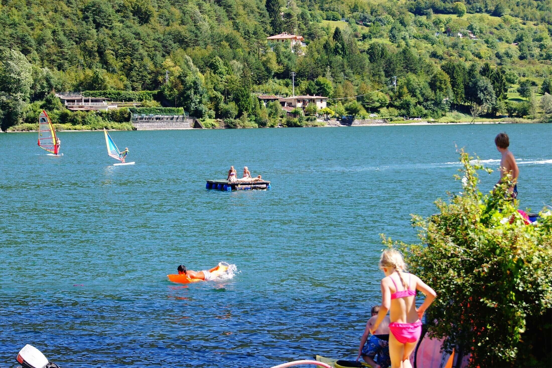 Ein See mit Windsurfern und Schwimmern.