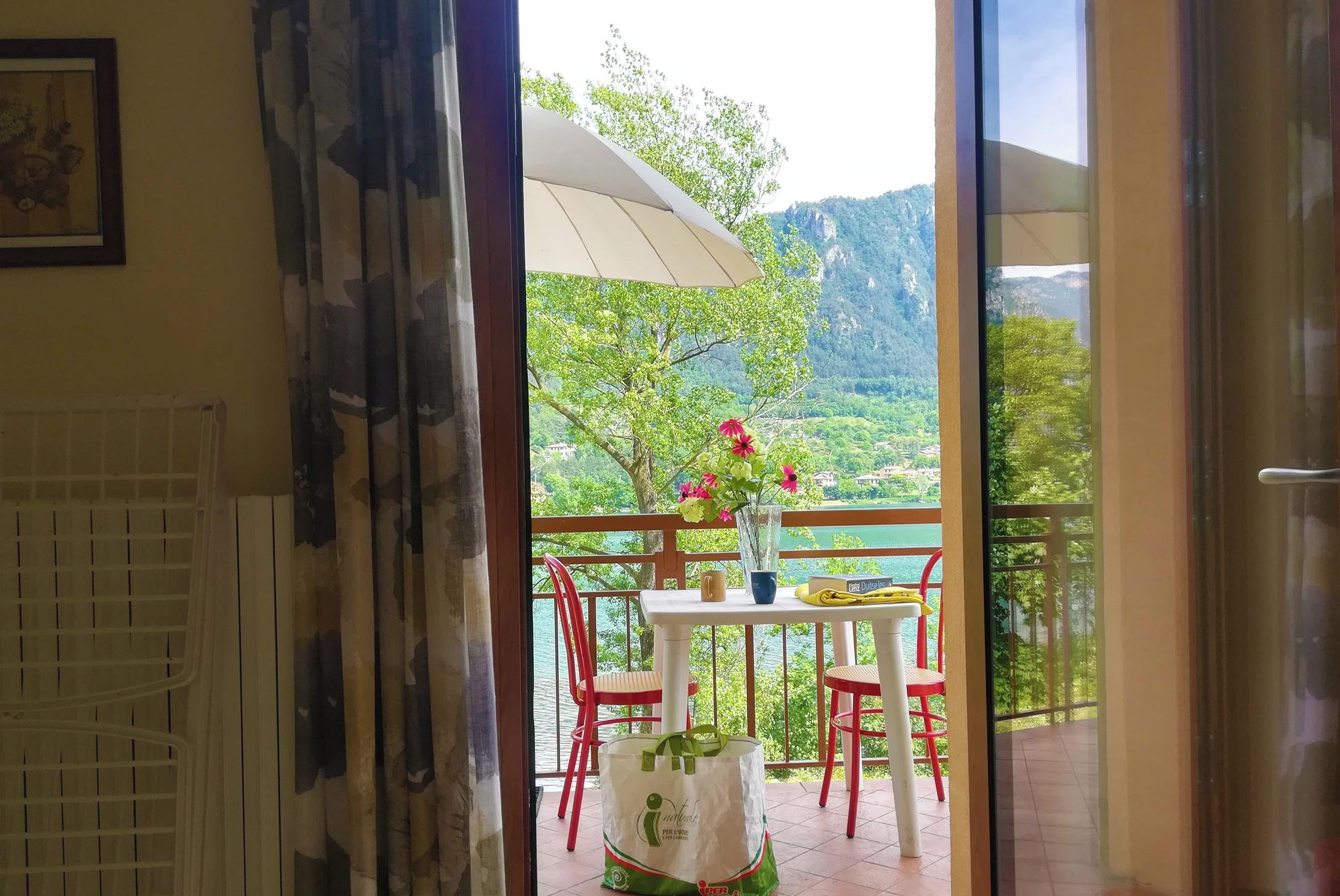 A balcony with a table, chairs, and a view of a lake and mountains.