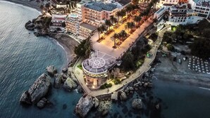 A coastal hotel with a central circular plaza, beachfront access, and multiple buildings with balconies. - Luxury Apartment with Private Garage and Communal Pool. FREE WIFI (Nerja)