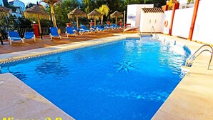 A swimming pool with blue water, surrounded by lounge chairs and umbrellas. - Luxury Apartment with Private Garage and Communal Pool. FREE WIFI (Nerja)