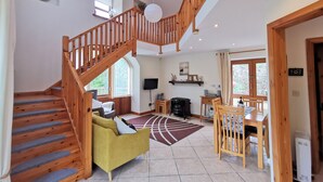 Un vaste espace de vie comprenant un escalier en bois, un canapé, une table à manger et une cheminée.