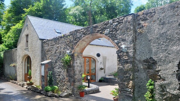 Un bâtiment en pierre avec une porte en bois, une petite fenêtre et un arc en pierre.