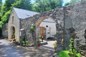Un bâtiment en pierre avec une porte en bois, une petite fenêtre et un arc en pierre.